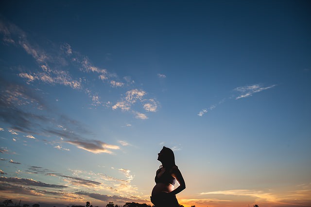 Kobieta w ciąży patrzy na zachód słońca