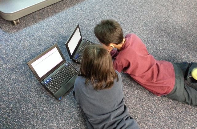 Dzieci leżące na podłodze z komputerami